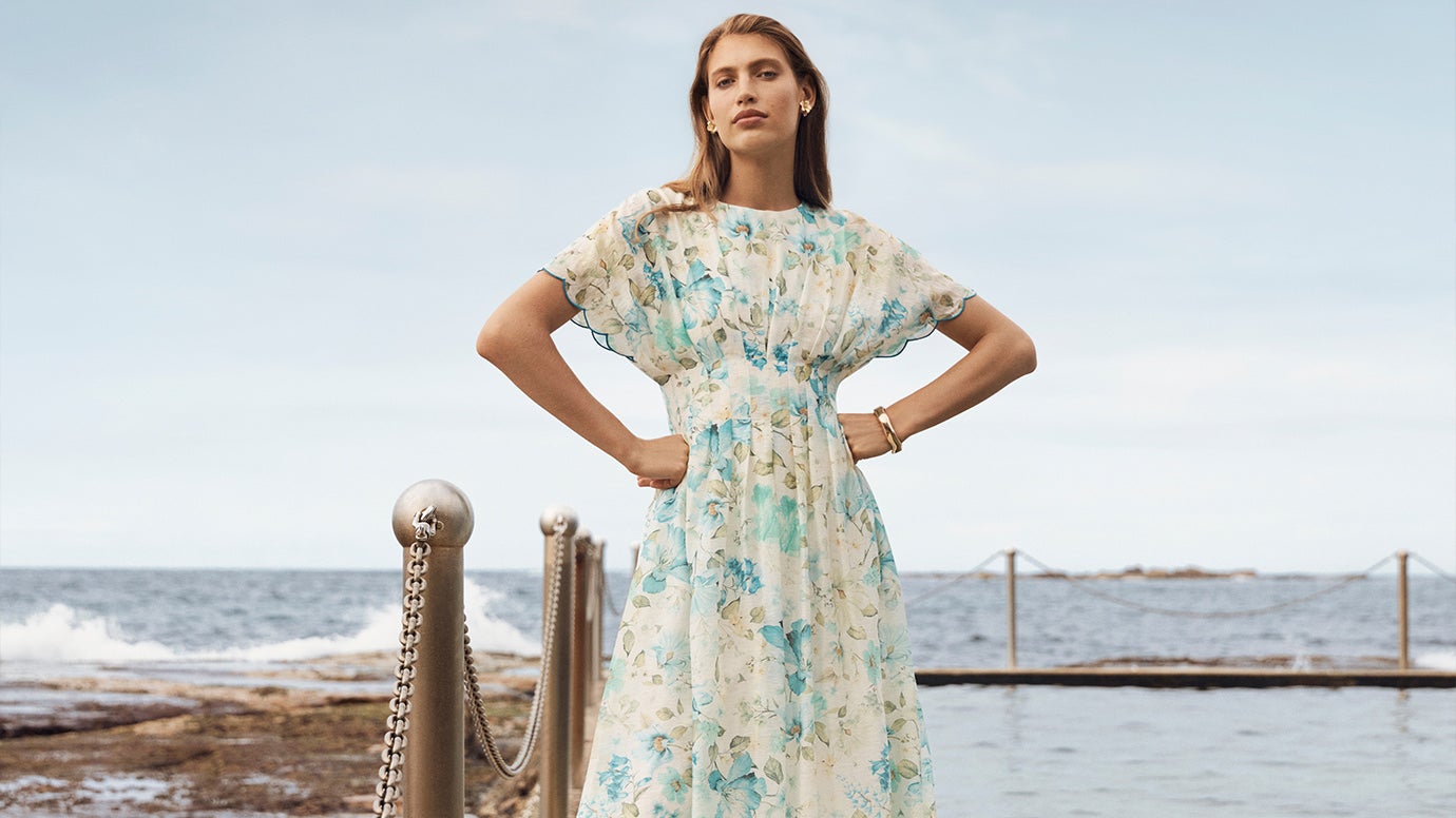 Model wears vintage-inspired floral dress as she lounges by the pool, the turquoise waters shimmering in the sunlight.