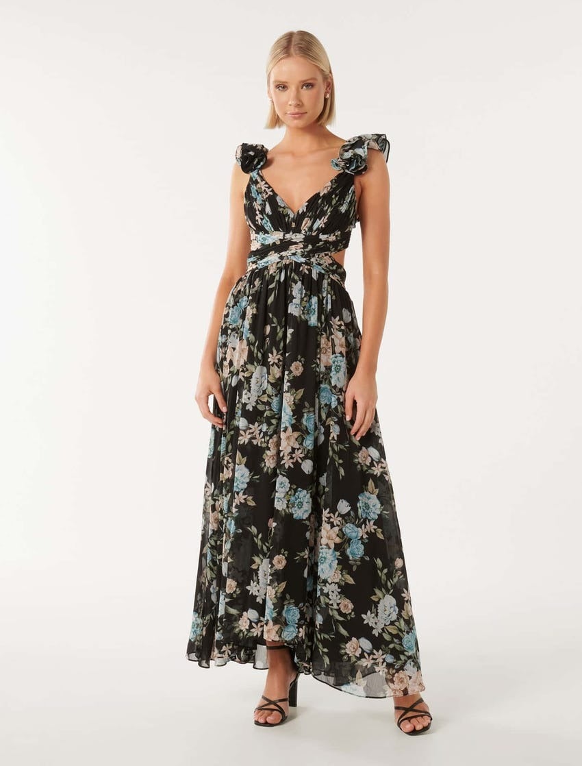 model with a blonde bob posing in a long flowing floral dress in black and blue