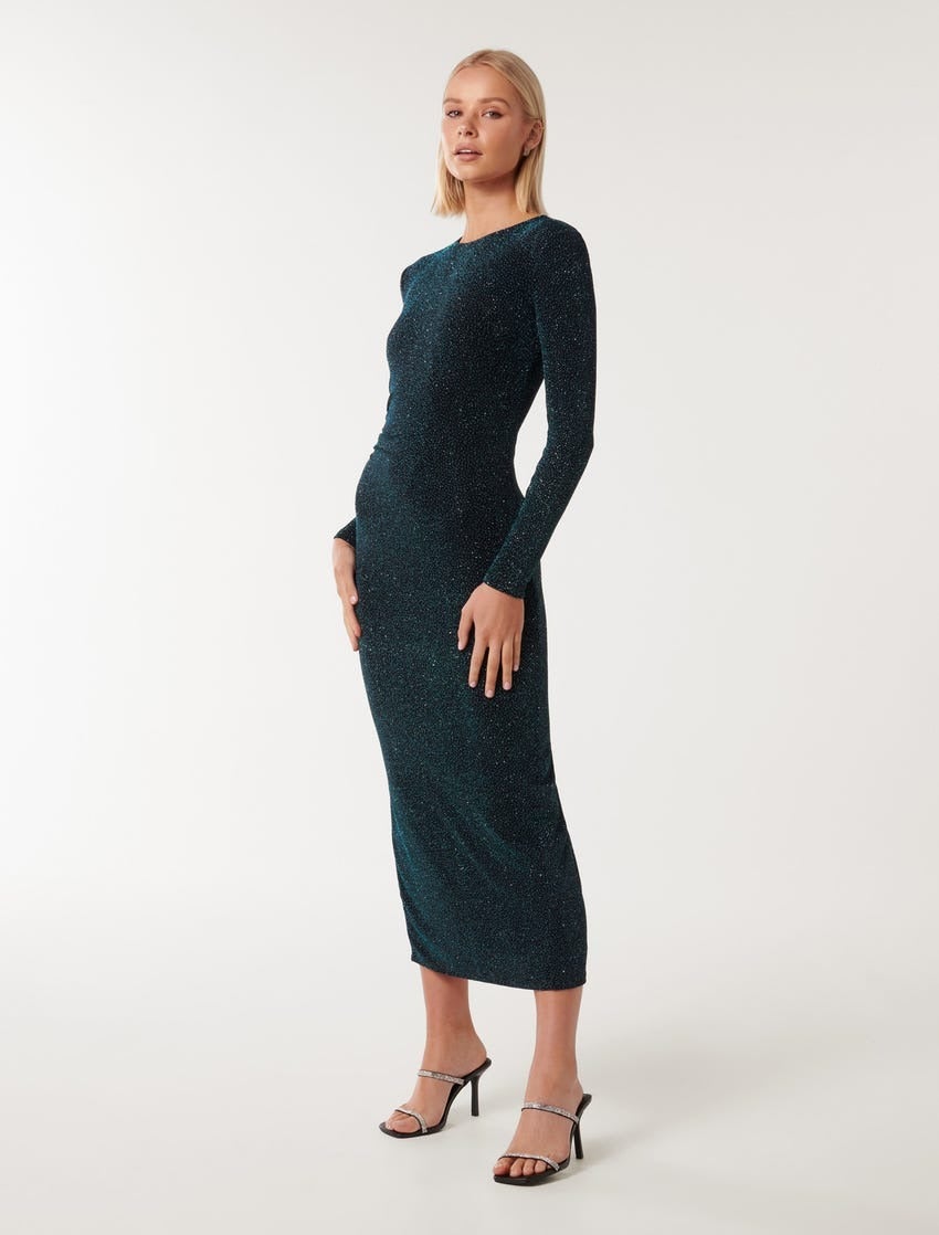 model with blonde bob wearing a long sleeve fitted teal green glitter dress with diamante embellished black heels 